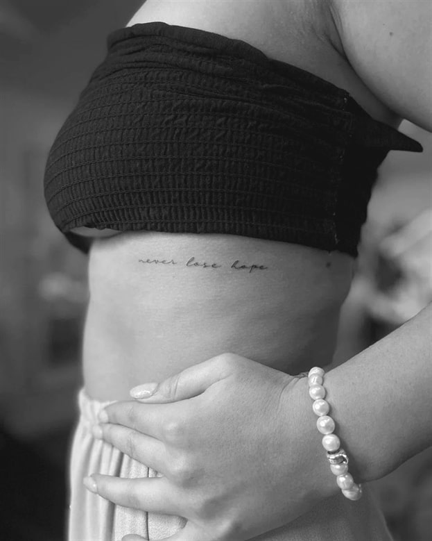 'never lose hope' script lettering tattoo gracefully on the rib hopeful reminder
