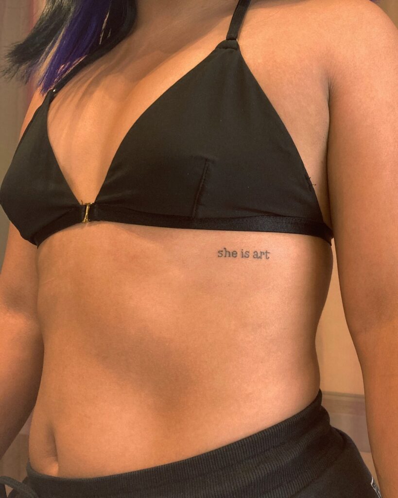 'she is art' words lettering tattoo on the rib: artistic soul
